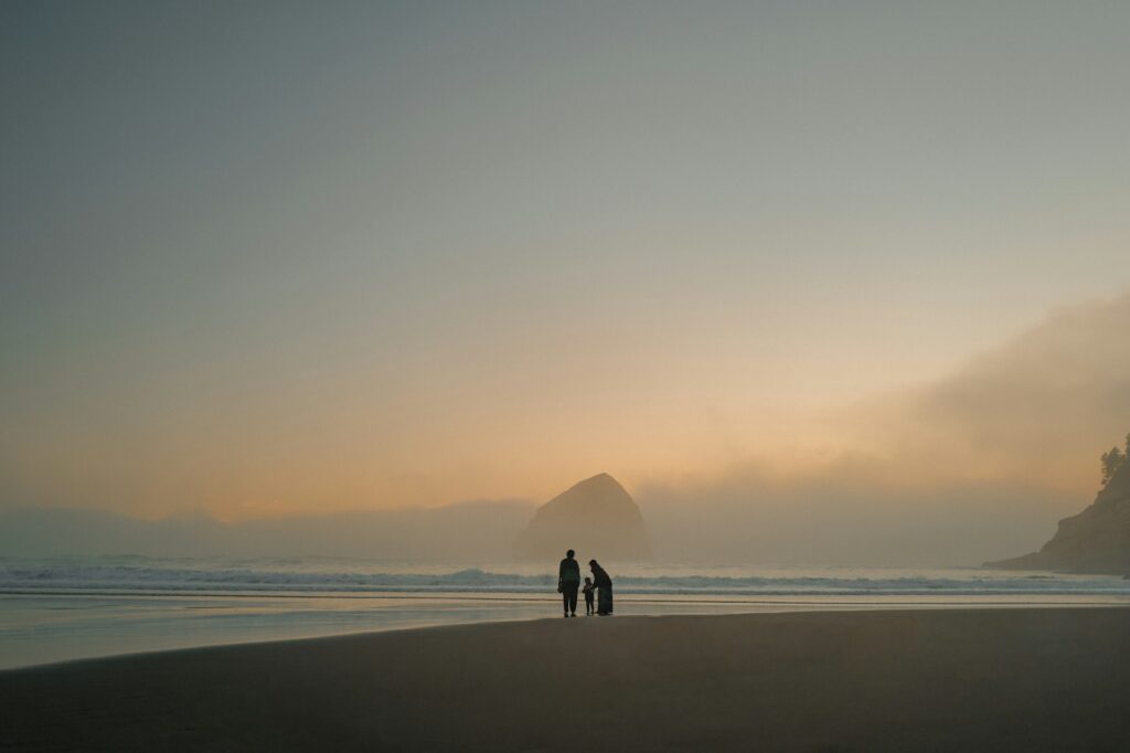 Family walking on a foggy beach at sunset