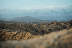Barren desert landscape with distant snow-capped mountains